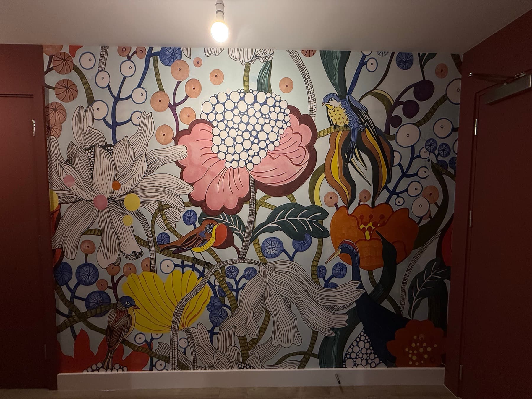 The mural wall head-on, the print running unbroken between two oxblood painted doors