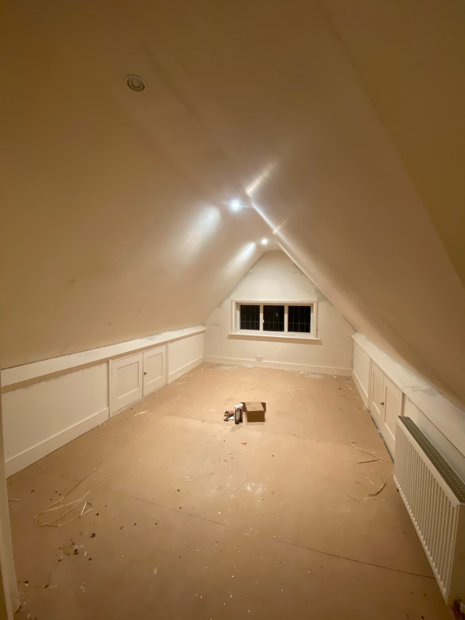 Loft bedroom before wallpapering — painted panelling and bare walls under the eaves