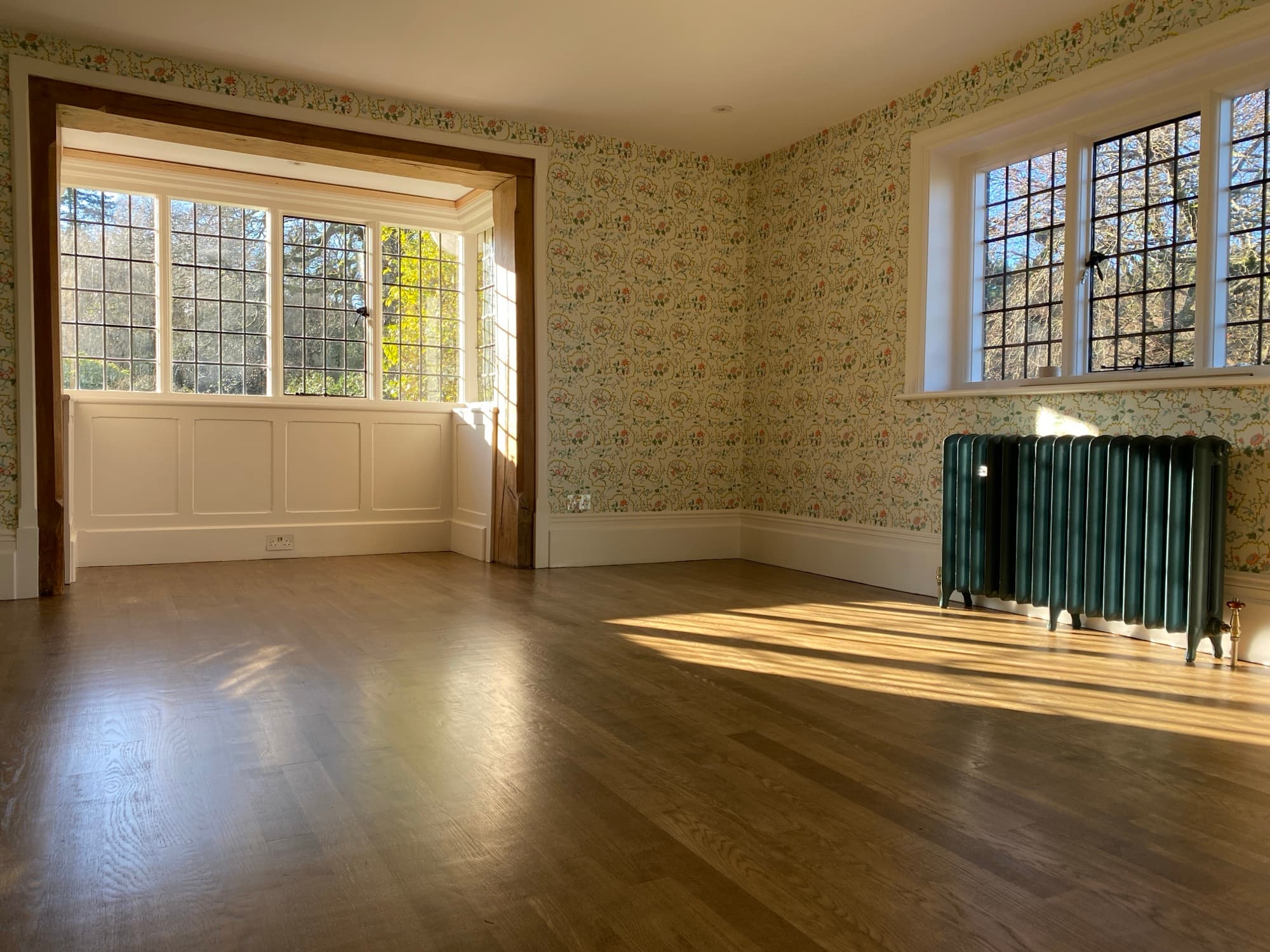 Reception room with floral wallpaper hung as a band above white painted wall panelling
